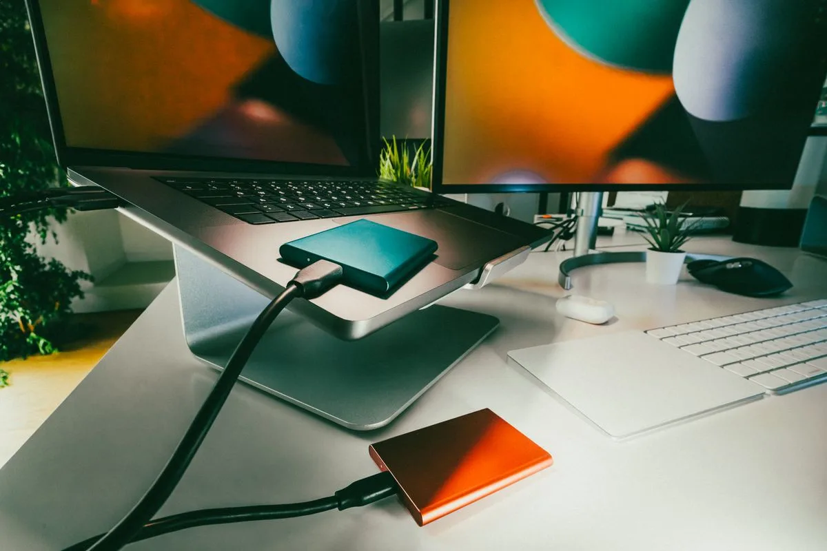 Setup de edição com dois SSDs portáteis conectados a um notebook sobre a mesa